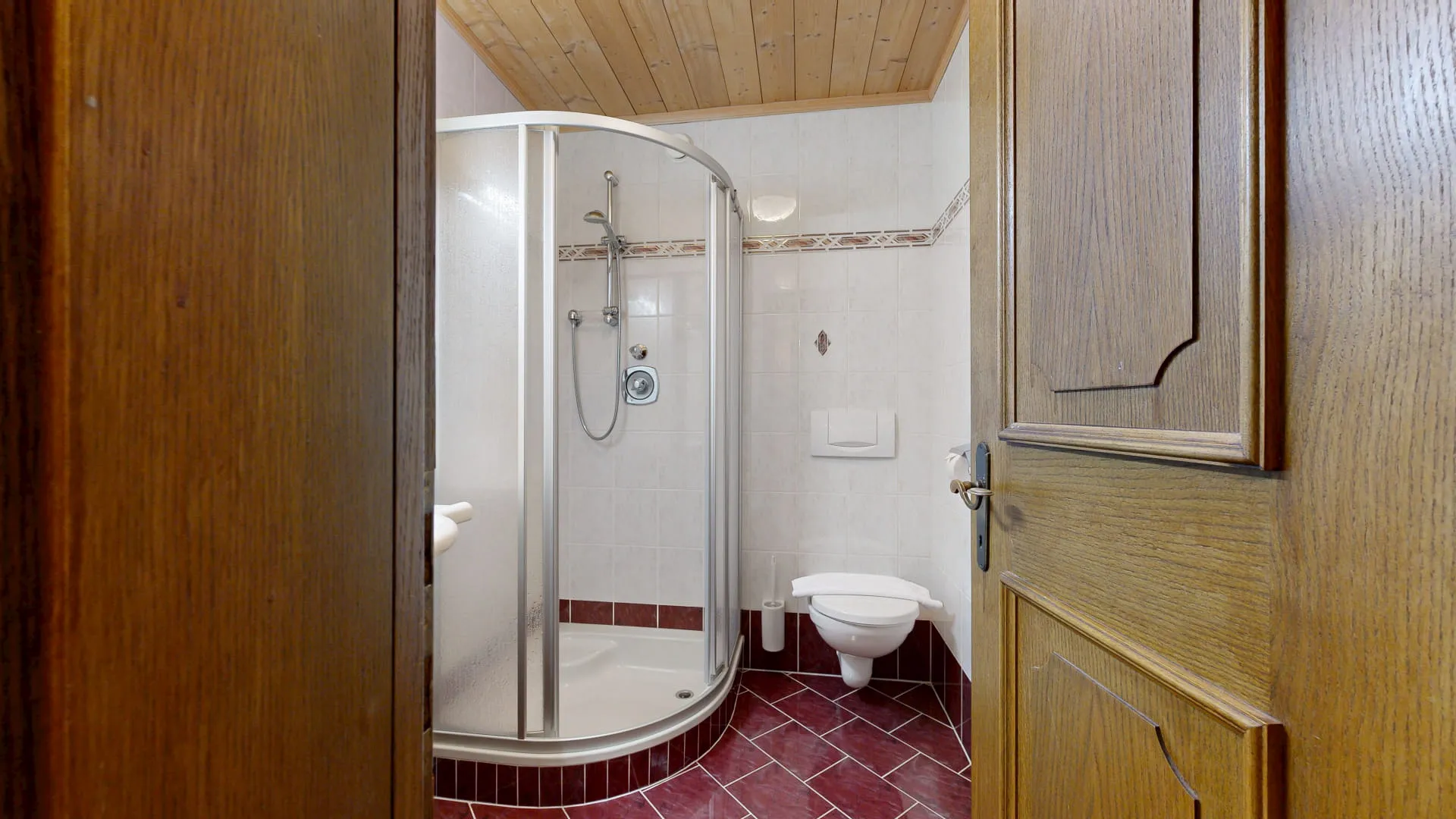 Blick auf ein Badezimmer mit Duschkabine und Toilette.
